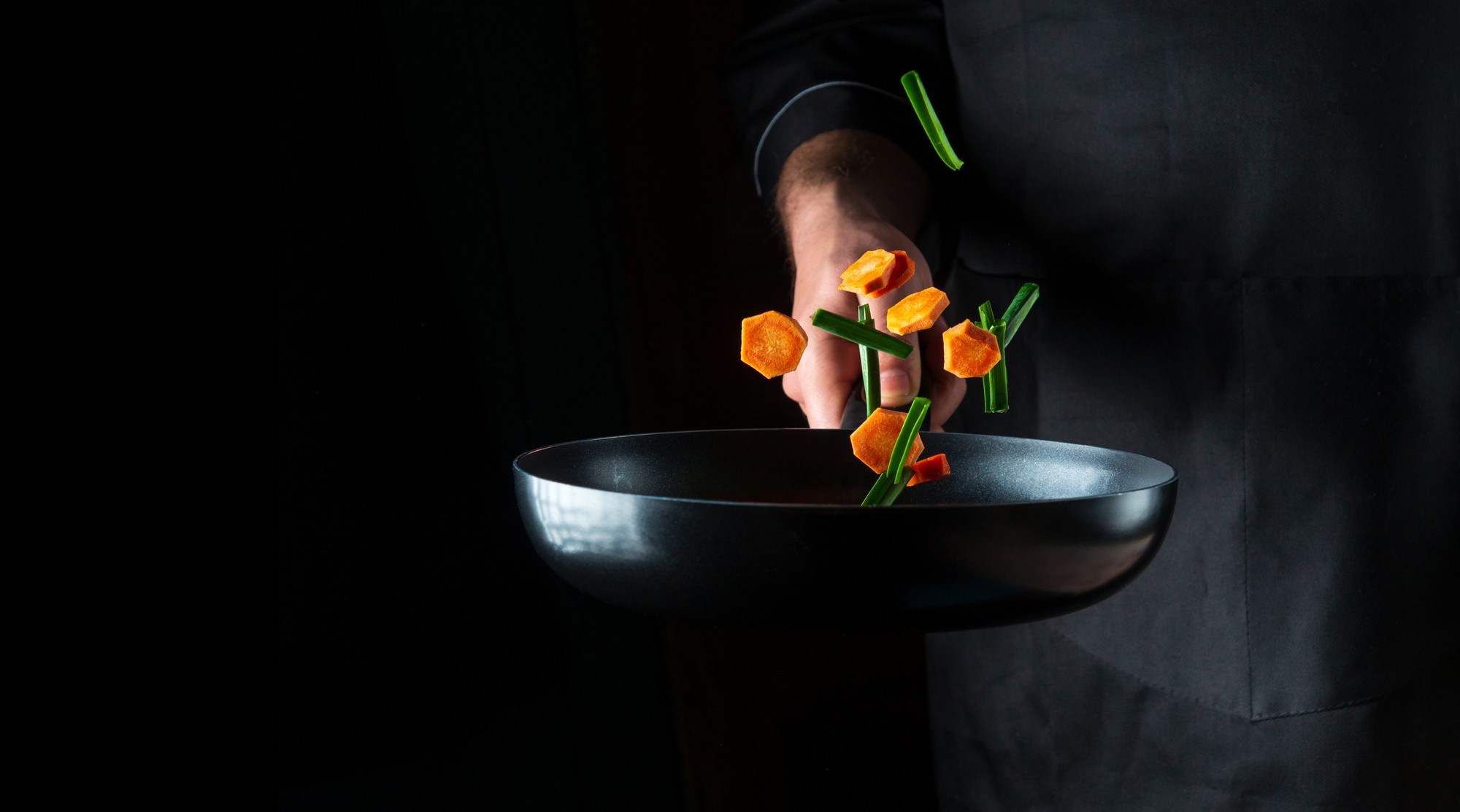Chef plating a refined dish on dark table